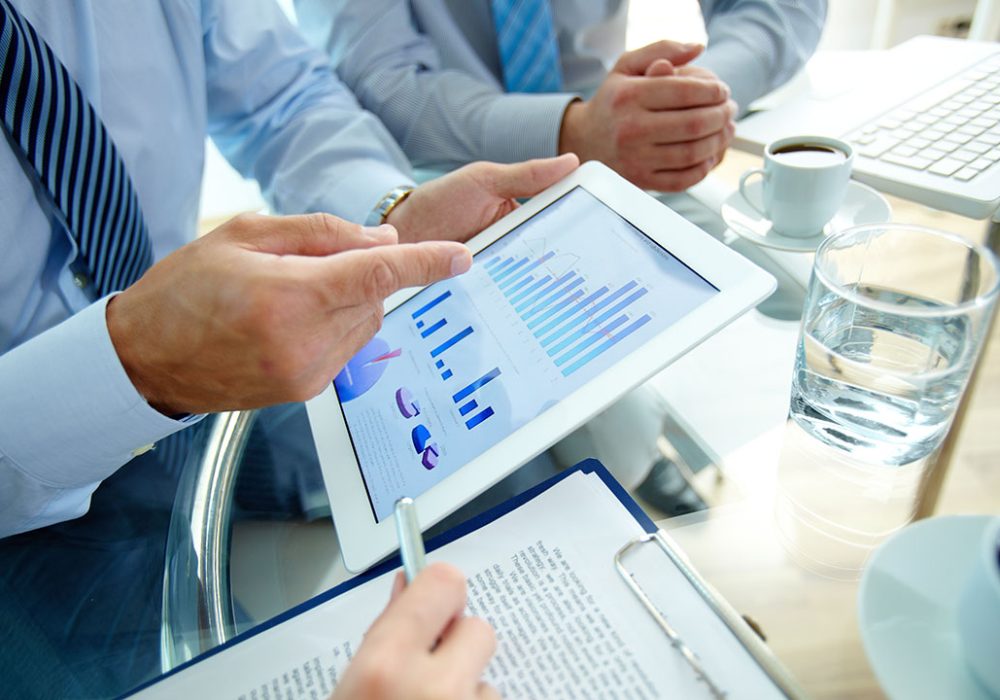 Modern people doing business, graphs and charts being demonstrated on the screen of a touchpad